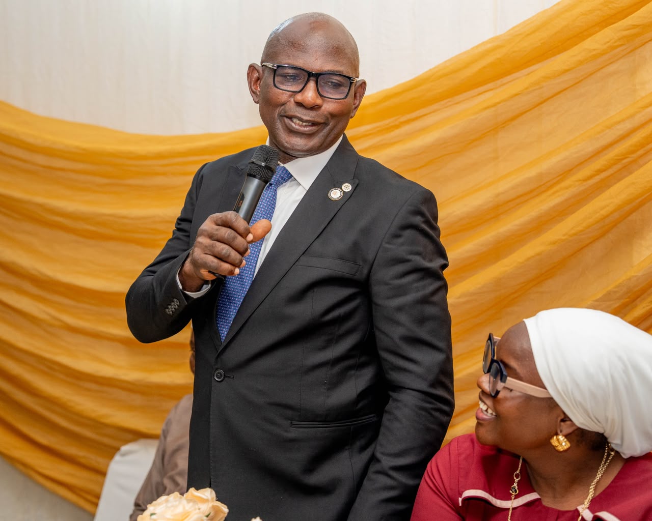 Kayode Abe speaking at a professional event in a dark suit