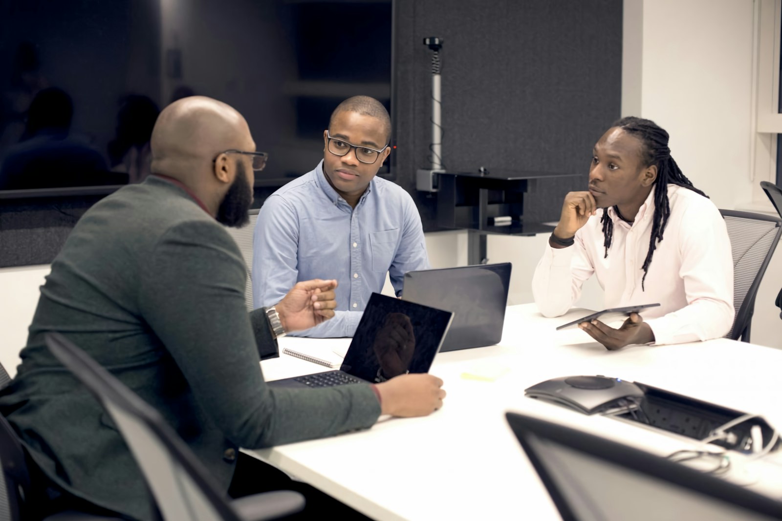 Three Black professionals sharing ideas around a table in a contemporary office